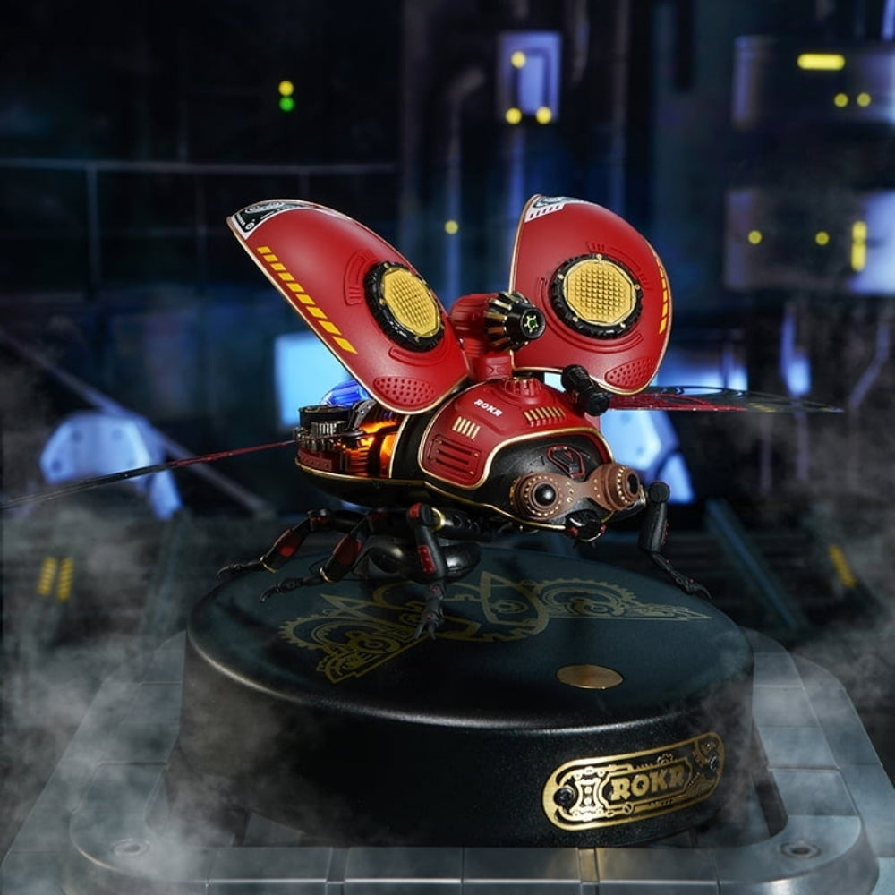 Red and yellow mechanical butterfly on a dark platform with a blurred background