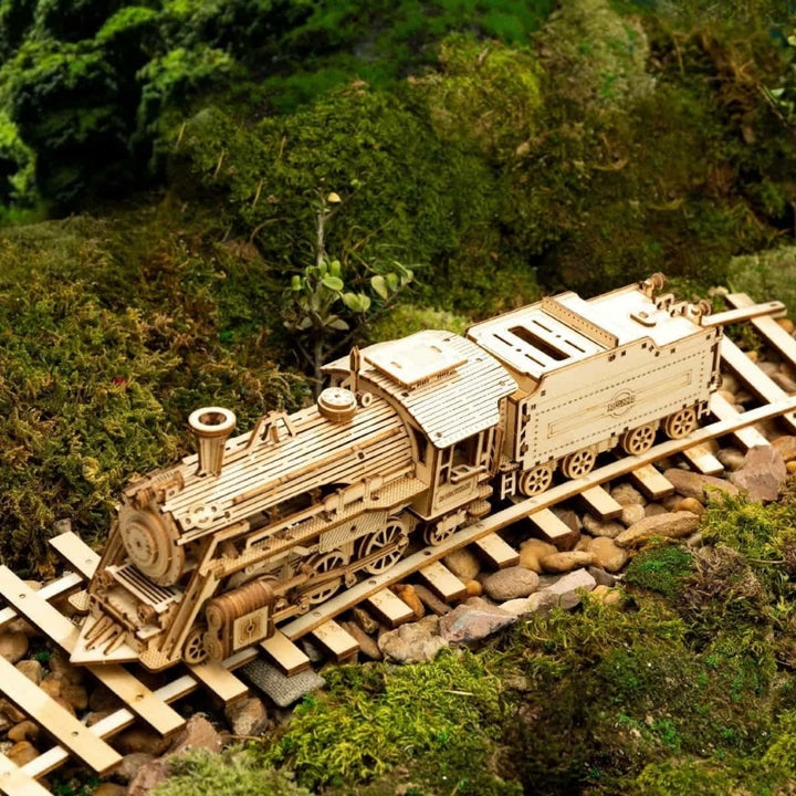 Wooden model train on a miniature railway track surrounded by greenery