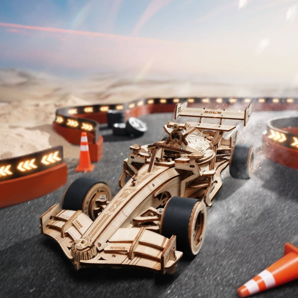 Wooden toy Formula 1 car on a race track with a desert landscape in the background
