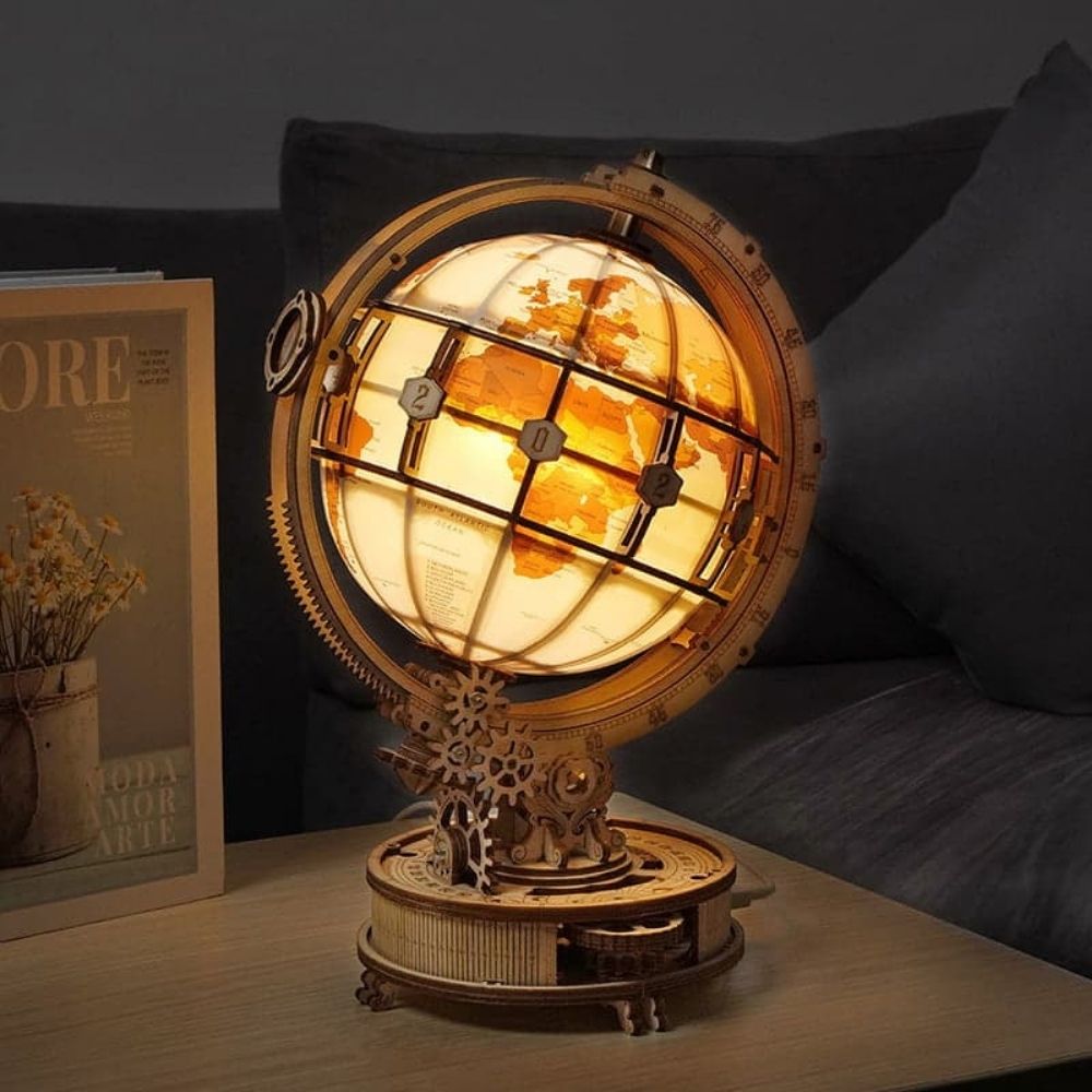 Decorative lamp with world map design on a table next to a magazine.