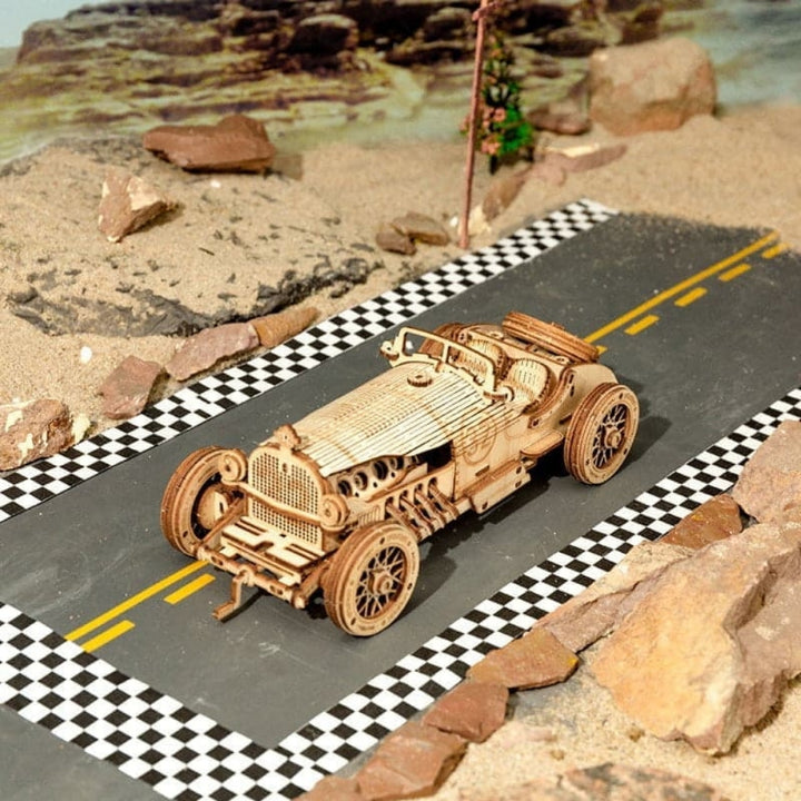 Wooden model car on a miniature road with checkered pattern and rocky surroundings