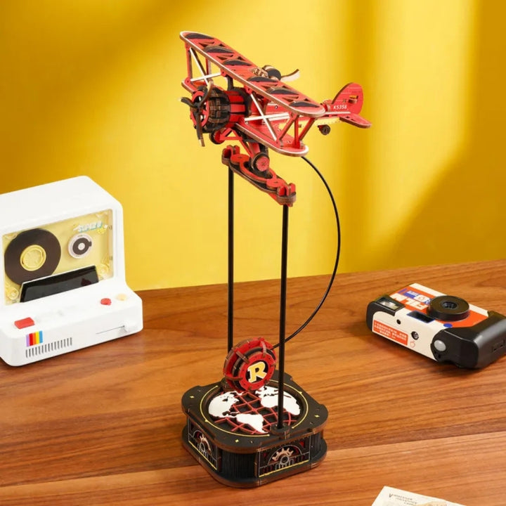 Red airplane model on a stand with vintage cameras in the background