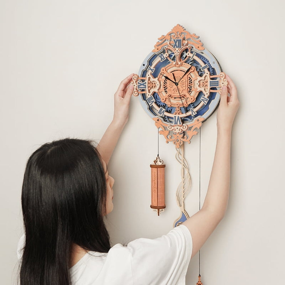Person adjusting a decorative wall clock with intricate design on a plain background