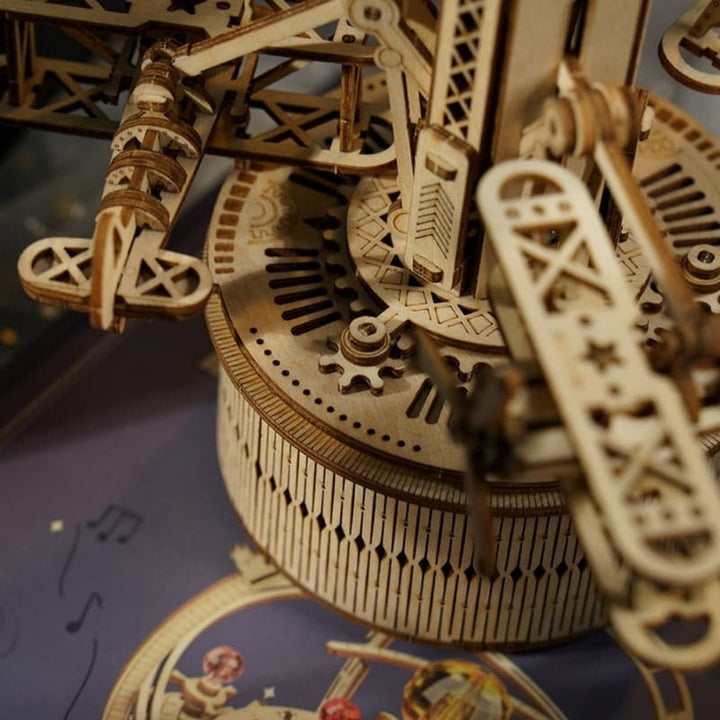 Close-up of a wooden mechanical model with intricate gears on a blue surface.