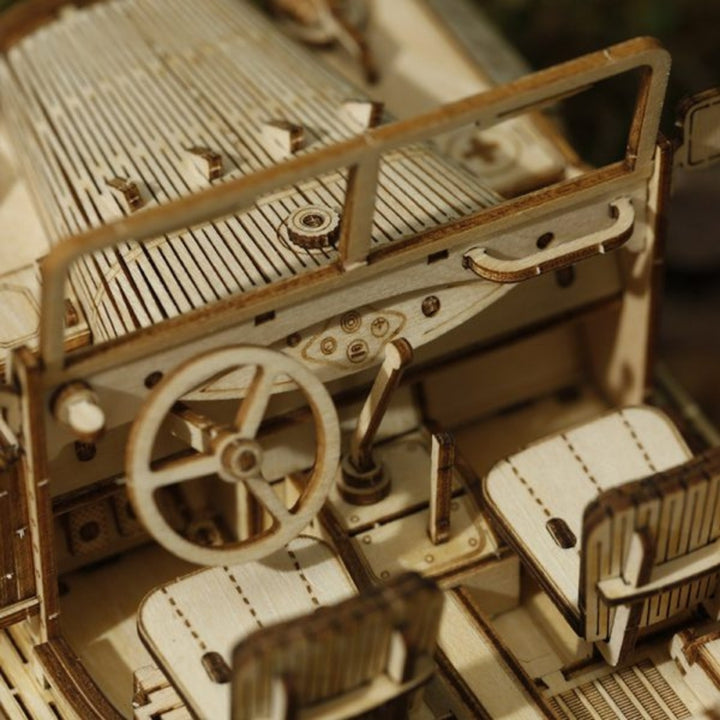 Close-up of a wooden model car with detailed interior and steering wheel.