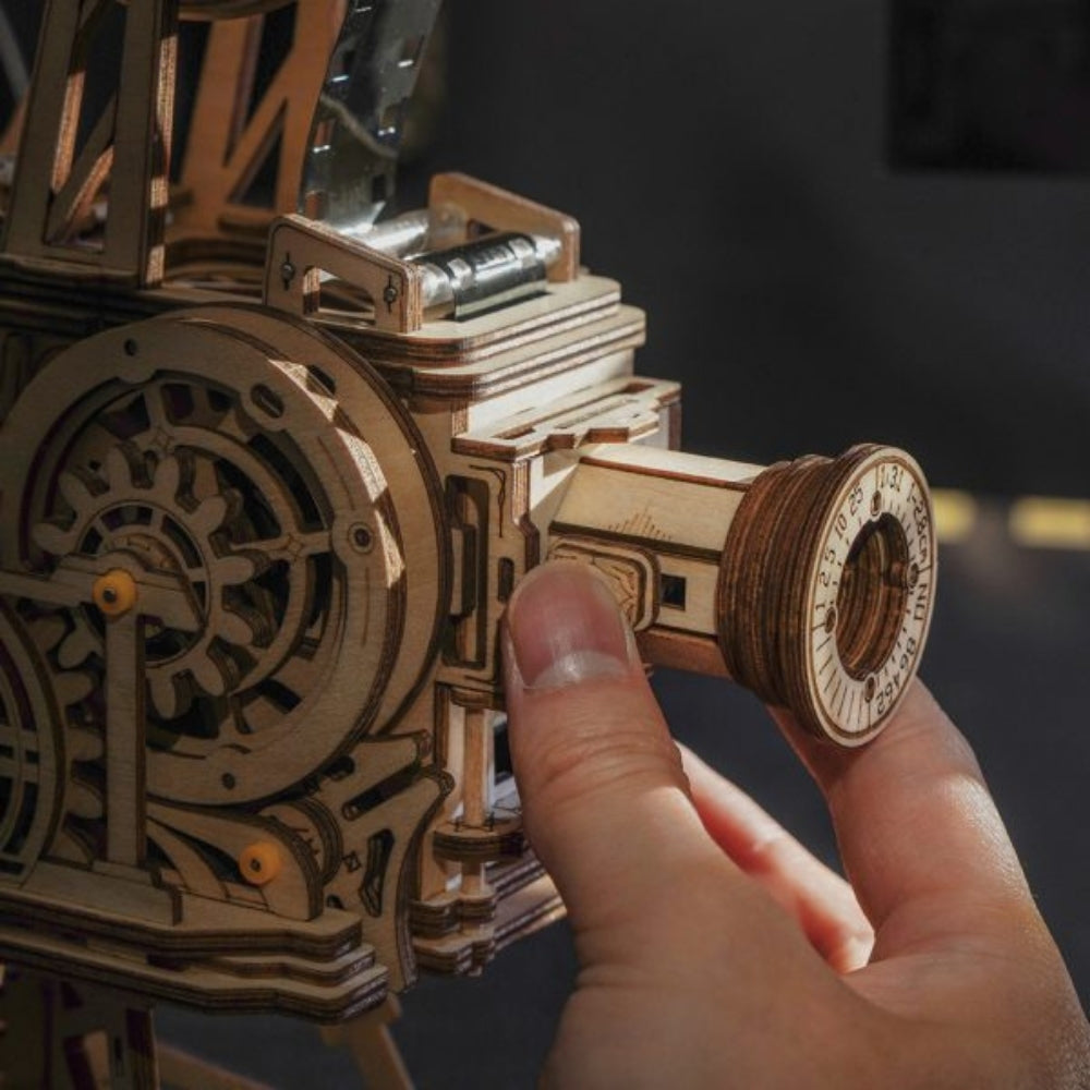 Hand interacting with a wooden mechanical model on a dark background