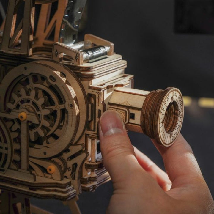 Hand interacting with a wooden mechanical model on a dark background