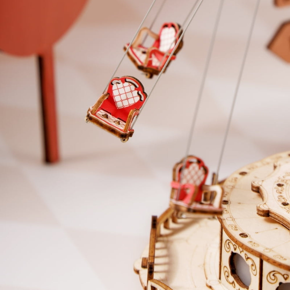 Wooden model of a carousel with red heart-shaped carriages on a white background