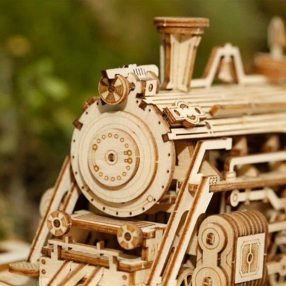 Wooden model of a steam locomotive with intricate details against a blurred natural background